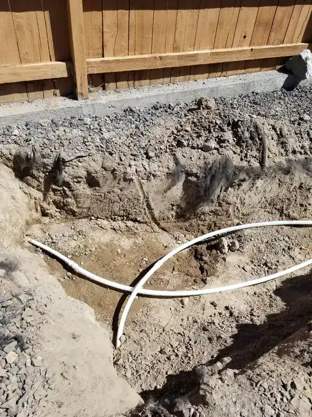 Excavated pit beside a fence with two new white lines crossing the bottom