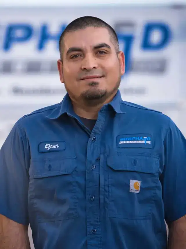 Efren Espinoza, Plumber at Shephard Plumbing, in a name-tagged work shirt in front of the box truck