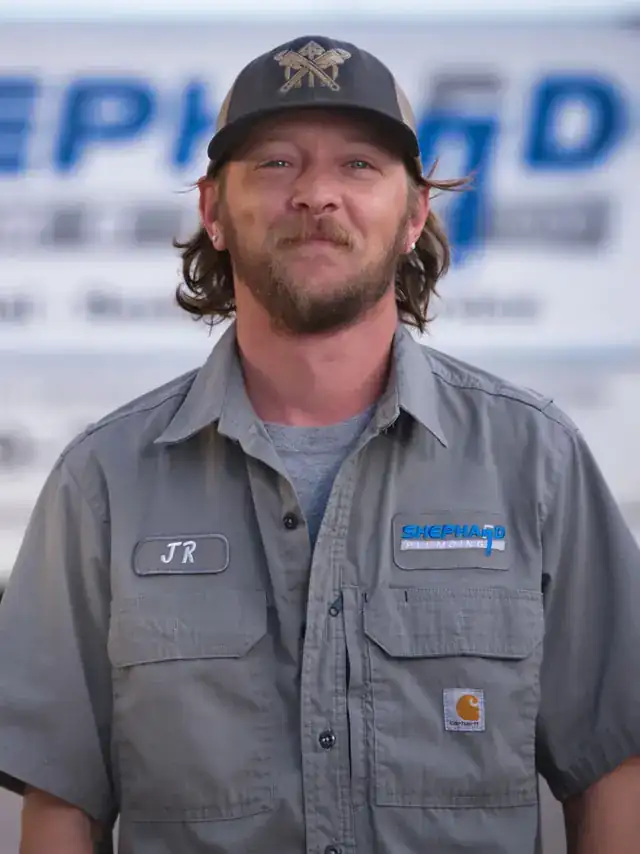 JR Baumbach, Plumber at Shephard Plumbing, in a name-tagged work shirt in front of the box truck