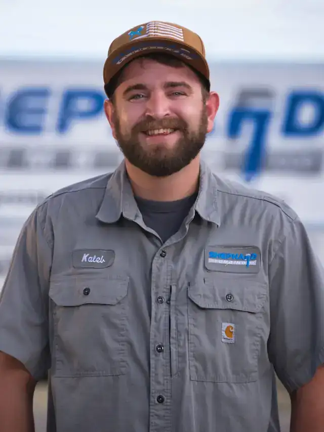Kaleb Curtice, Plumber at Shephard Plumbing, in a name-tagged work shirt in front of the box truck