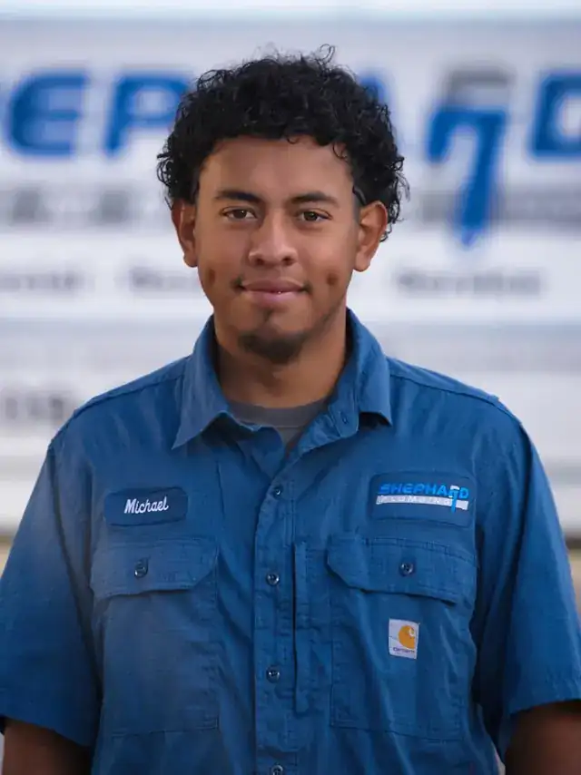 Michael Silva, Plumber at Shephard Plumbing, in a name-tagged work shirt in front of the box truck