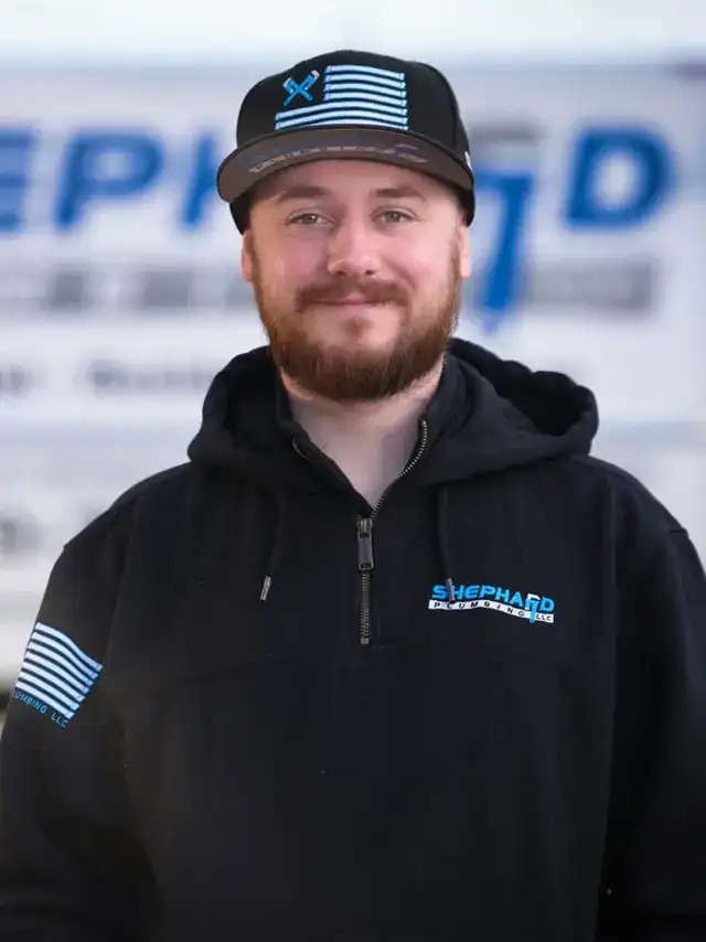 Tanner DeJournette, GM at Shephard Plumbing, in a name-tagged work shirt in front of the box truck