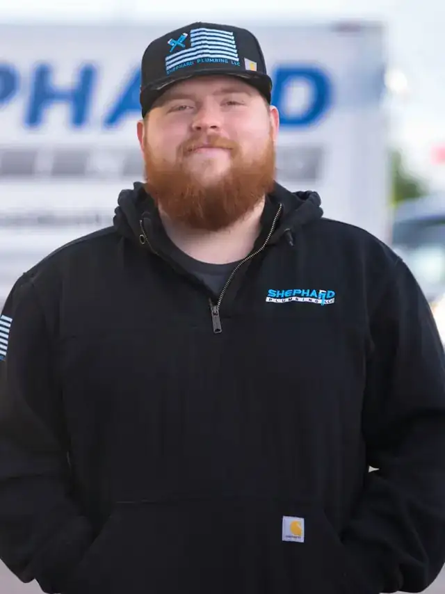 Tim Williams, Plumber at Shephard Plumbing, in a name-tagged work shirt in front of the box truck