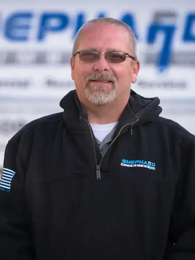 Wayne Shelton, Plumber at Shephard Plumbing, in a name-tagged work shirt in front of the box truck